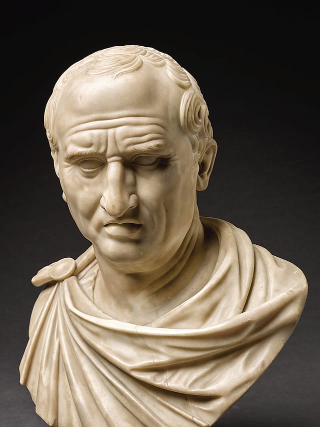 Marble bust of an older man in robes with short hair.
