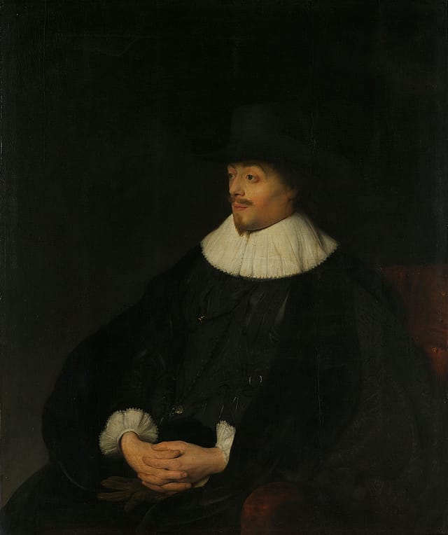 Painting of a man sitting in front of a dark background. He is wearing a black hat and white collar. He has a moustache and goatee.