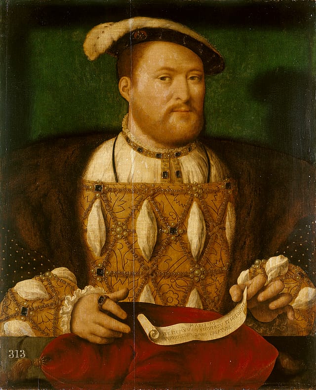 Half-portrait painting of Henry VIII set against a green background. He is wearing a floppy cap, and a jacket with a fur collar. His linen shirt beneath his doublet has been pulled through slashes in the cloth of gold fabric to form elliptical puffs of fabric. In front of him a scroll sits on a red velet pillow.