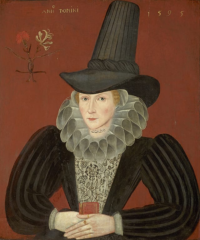 Half-portrait painting of a middle-aged woman in front of an orange-red background. She is wearing a large, black top hat; a large, frilly, white collar; and a black, long-sleeve corset with a white and black pattern on the bust. She is also wearing a necklace composed of several strands of tiny beads and on her left hand she has three rings. One has an amber-coloured stone in a conventional quatrefoil bezel. On her small finger is a plain double hoop and her thumb has another double hoop. She holds a small book.