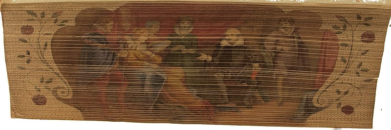 Painting on the fore-edge of an old book. Six figures are sitting in a comfortable interior setting. Second from the right is William Shakespeare who is gesturing to Queen Elizabeth sitting second from the left. Behind the figures there is a large, red curtain.