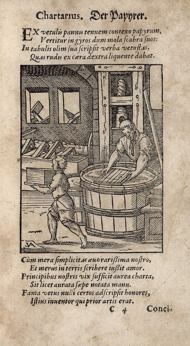 Page from an old book with lines of printed text and an engraving depicting a man and a child making paper. In the foreground, the man stands over a pulp-filled tub holding a screen while the boy carries sheets of paper. In the background, there is a press and a hammer for beating pulp. Waterwheels can also be seen through the two windows.